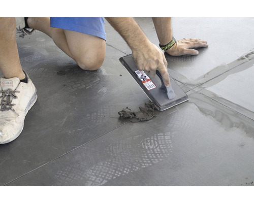 Persoon voegt tegels met een voegbord