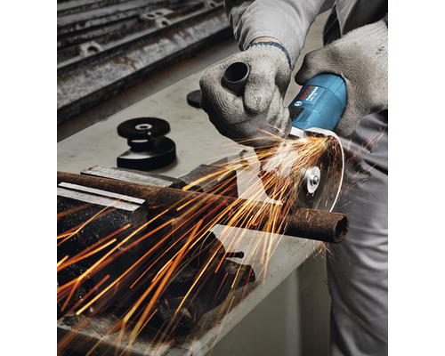 Een persoon snijdt een metalen buis met een haakse slijper. Vonken vliegen.