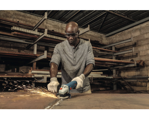 Een man slijpt metaal met een haakse slijper, waarbij vonken vrijkomen.