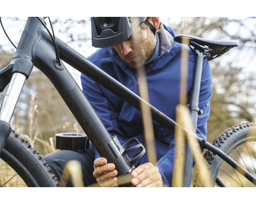 Man bevestigt met ducttape een bidonhouder aan een fiets.