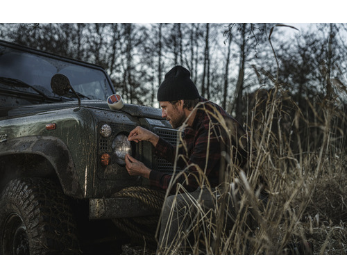Man bevestigt tape aan koplamp van terreinwagen