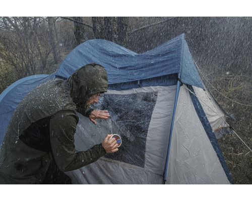 Persoon maakt tentraam schoon in regenachtig weer.