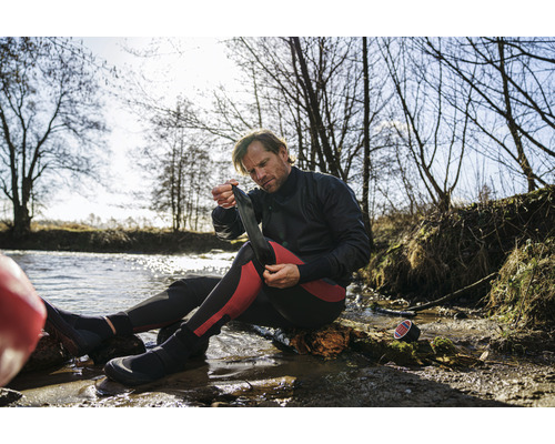 Man trekt neopreen sokken aan bij het water