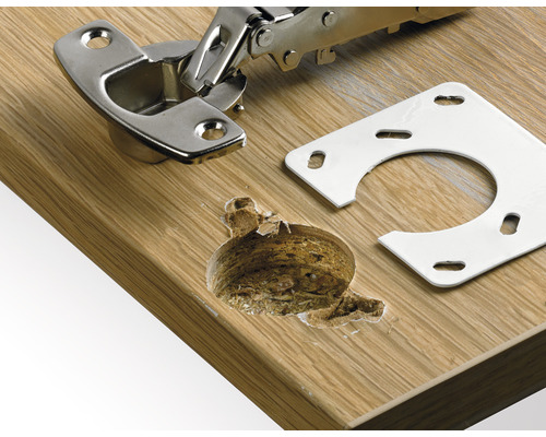 Meubelscharnier met montageplaat op een houten oppervlak en boorgat