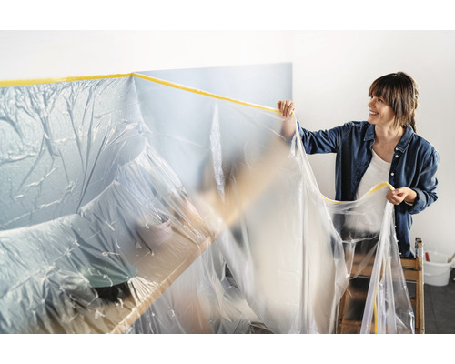 Vrouw bevestigt afdekfolie met tape voor renovatiewerkzaamheden