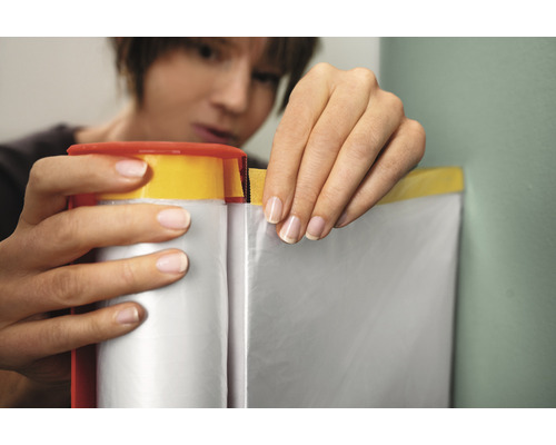 Vrouw gebruikt afplakband met folie om oppervlakken te beschermen tijdens het schilderen