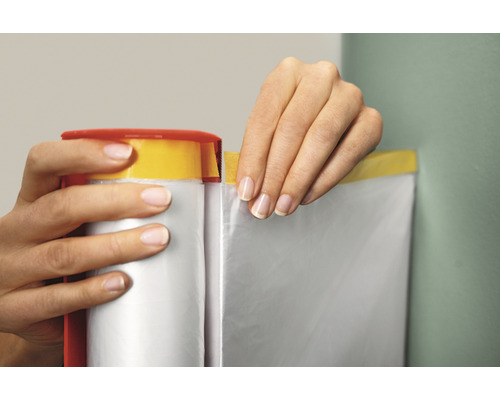 Een persoon gebruikt afdekfolie met plakband om een muur af te dekken.