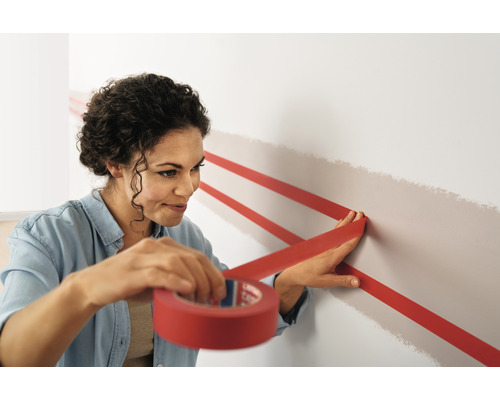 Vrouw plakt schilderstape op een muur