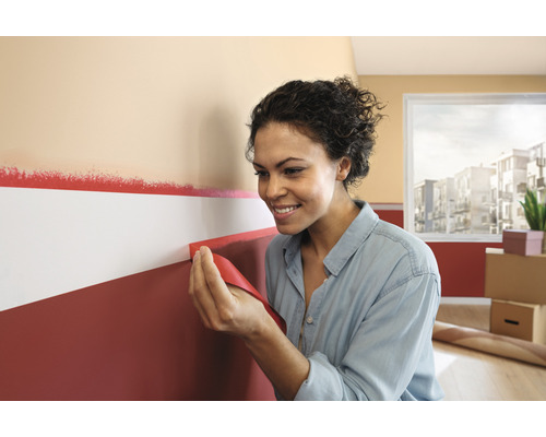 Vrouw verwijdert schilderstape van een muur met verf.