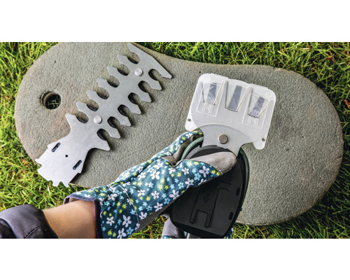 Een hand met tuinhandschoen houdt een heggenschaarslijper vast, naast een apparaat voor het uitlijnen van heggenscharen