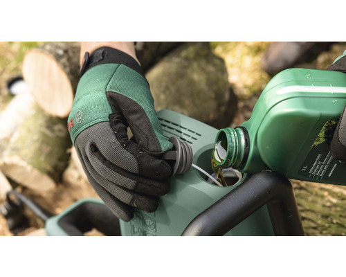 Een persoon vult kettingolie in een kettingzaag.