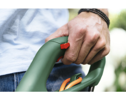 Hand houdt een grastrimmer met veiligheidsschakelaar vast