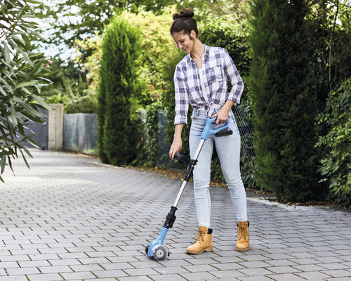 Vrouw gebruikt een voegenborstel voor het reinigen van een stenen pad.