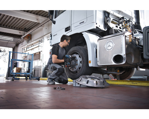 Een monteur verwisselt een wiel van een vrachtwagen in een werkplaats.