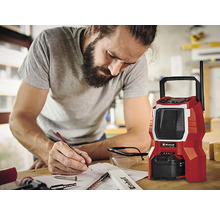 Een man maakt aantekeningen naast een rode bouwradio van het merk Einhell.