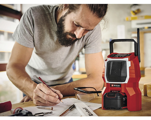 Een man maakt aantekeningen naast een rode bouwradio van het merk Einhell.