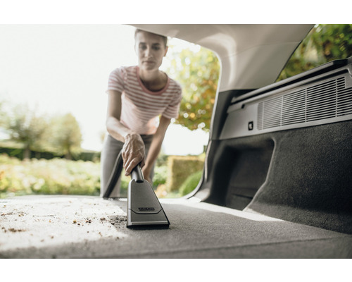 Vrouw zuigt de kofferbak van een auto met een Kärcher stofzuiger.