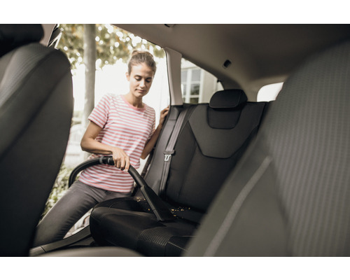 Vrouw stofzuigt autostoelen met een stofzuiger.