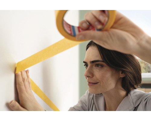 Vrouw brengt schilderstape aan op de muur