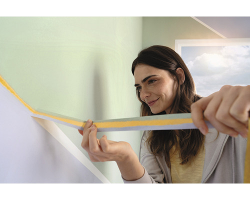 Vrouw brengt afplakband aan op een muur