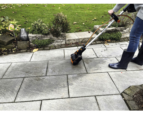 Persoon gebruikt een voegenborstel voor het reinigen van stenen platen buitenshuis.