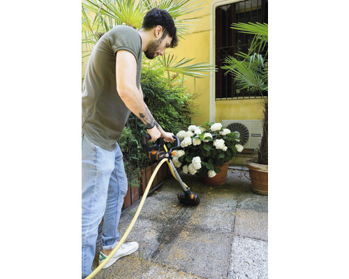 Man reinigt terras met terrasreiniger.