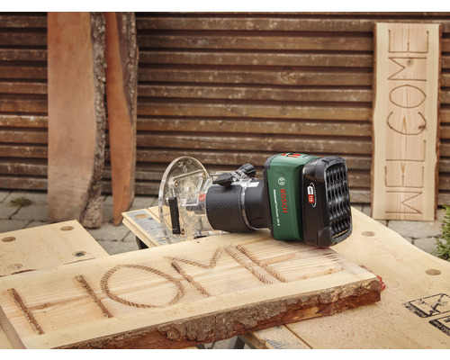 Accufrees bij het graveren van het woord HOME in een houten plank, op de achtergrond een plank met het woord WELKOM