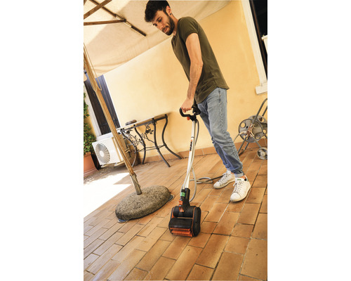 Man reinigt een terras met een elektrische terrasreiniger.