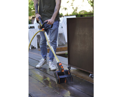 Een persoon gebruikt een terrasreiniger om een houten terras schoon te maken.