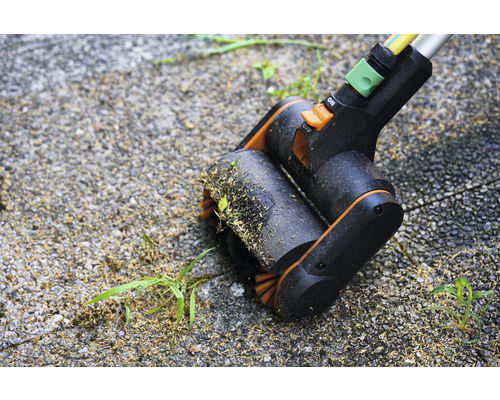 Voegenborstel in actie bij het verwijderen van onkruid op een bestrate oppervlakte.