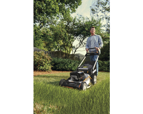 Man duwt een gazonmaaier in de tuin.