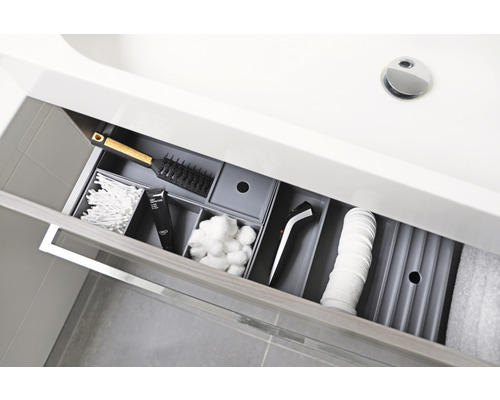 Geopende lade onder een wastafel met toiletartikelen en een haarstylingapparaat voor opslag