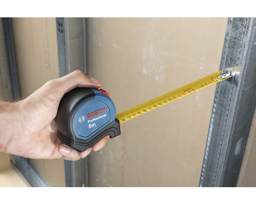 Hand houdt Bosch rolmaat van 5 meter lang vast aan metalen frame