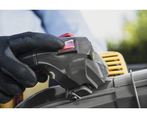 Hand met beschermende handschoen bedient schakelaar van een bladblazer