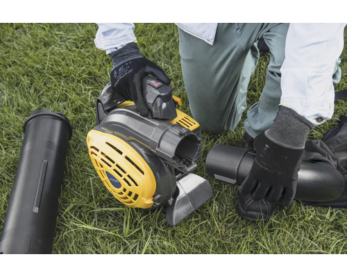 Iemand monteert een geelgrijze bladblazer op een gazon.