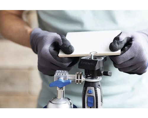 Een persoon fixeert een tegel met een Dremel gereedschap.