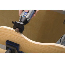 Dremel multifunctioneel gereedschap dat een stuk hout schuurt dat in een bankschroef is bevestigd