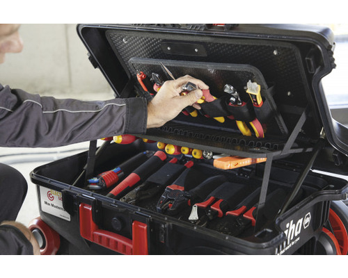 Geopende gereedschapskist met diverse gereedschappen, bediend door een persoon