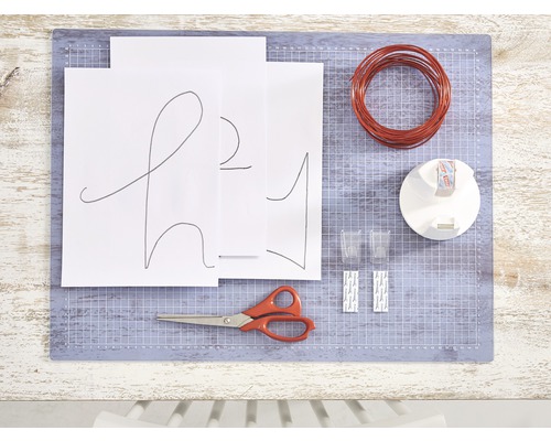 Materialen voor een doe-het-zelfproject op een snijmat, inclusief draad, schaar en papier