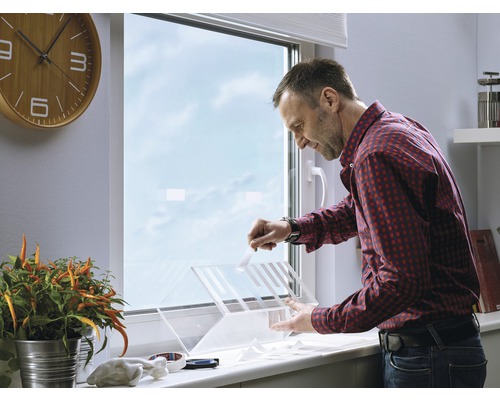 Een man installeert een insectenhor op een raam.