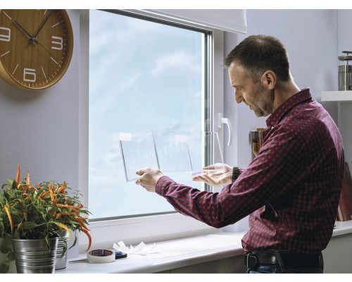 Man bevestigt een transparante folie op een raam.
