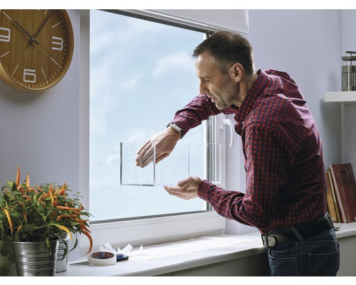 Man brengt isolerende folie aan op een raam voor thermische isolatie.