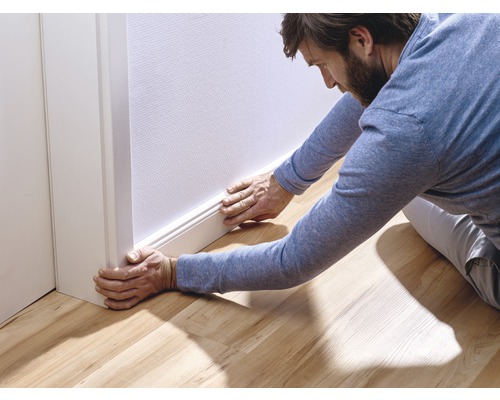 Man installeert een plint aan een muur