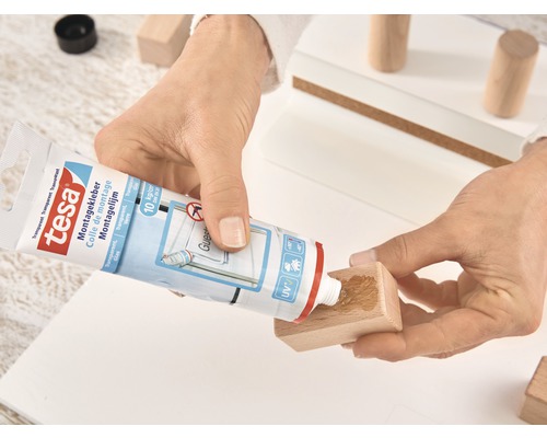 Iemand brengt Tesa montagekit aan op een stuk hout.