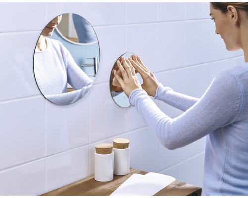 Vrouw bevestigt ronde spiegel aan badkamermuur