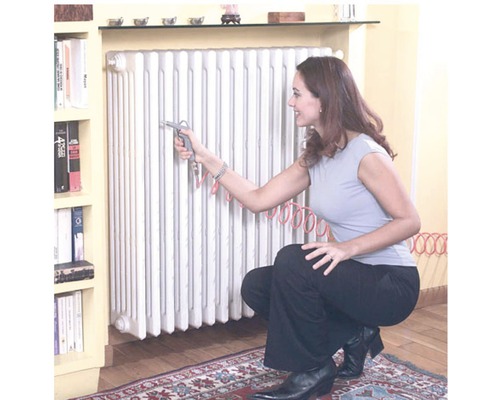 Vrouw reinigt radiator met persluchtpistool