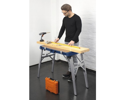 Man werkt met een werkbank, een accuschroevendraaier, schroeven en een meetlint aan een houten plank.