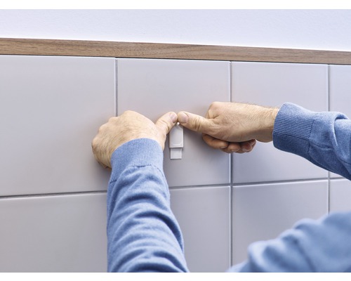 Persoon bevestigt een haak aan een betegelde muur