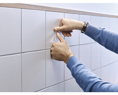 Bevestiging van zelfklevende strips op tegels