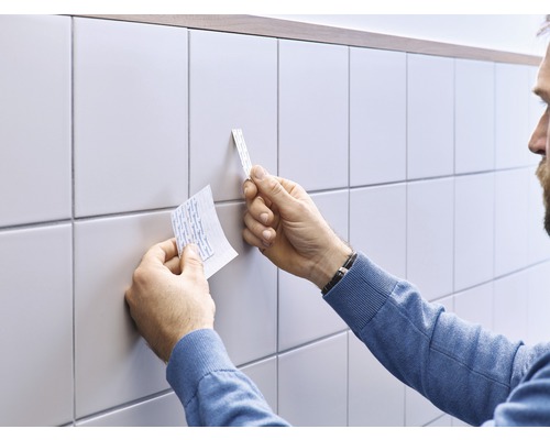 Een persoon bevestigt dubbelzijdige tape op tegels